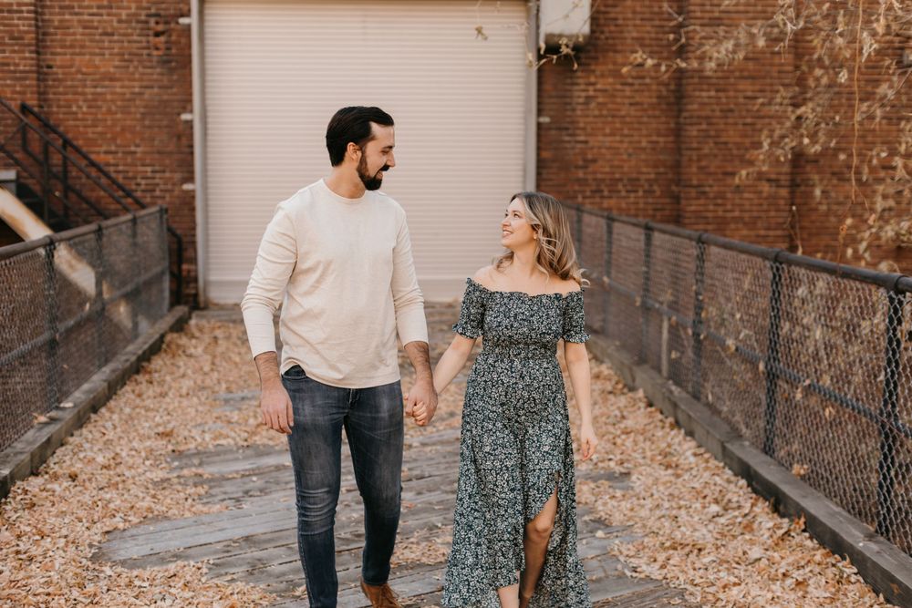 Happy couple holding hands and walking through a charming brick alley on a sunny day.