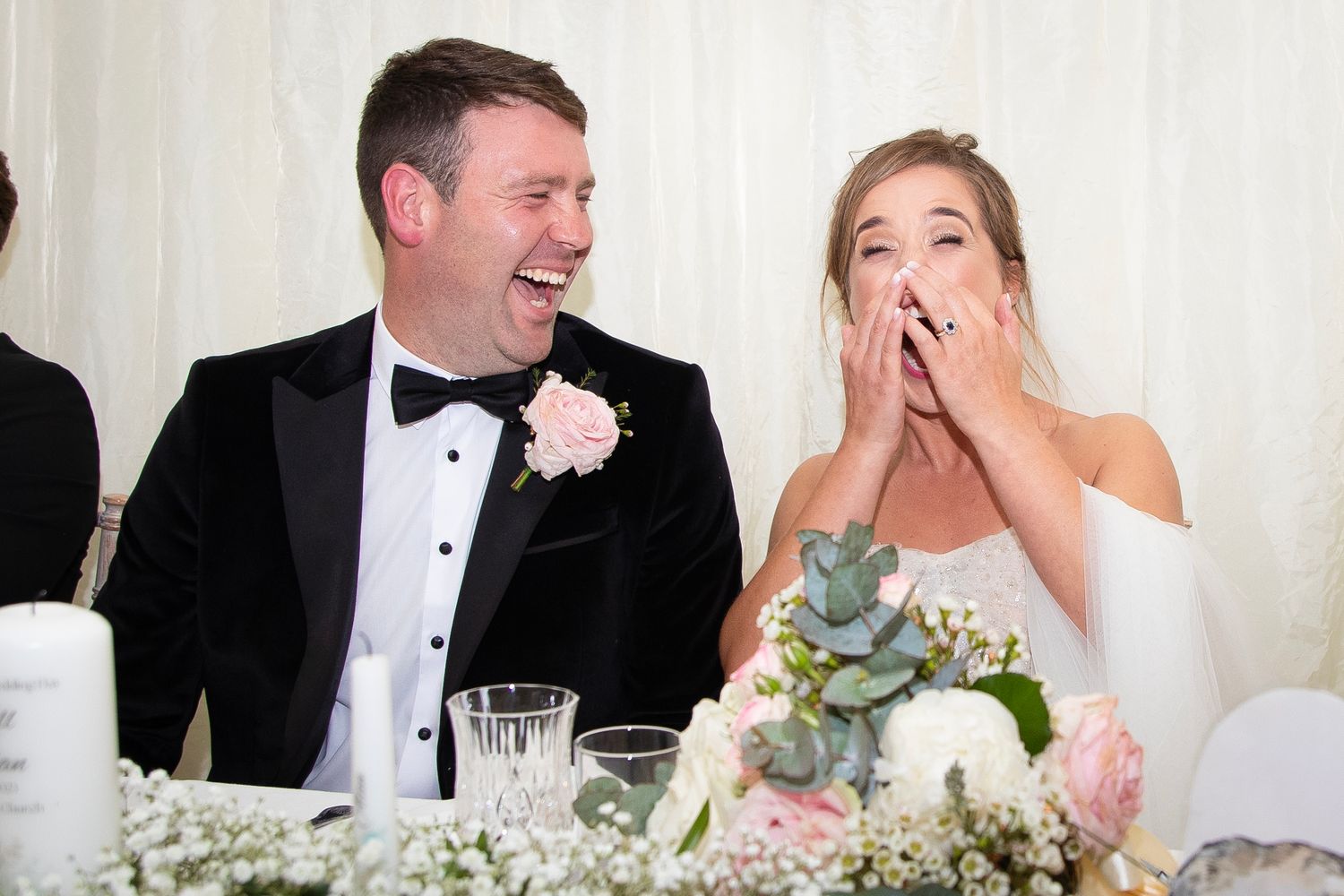 Candid moment of shared laughter during a wedding reception at a decorated table.