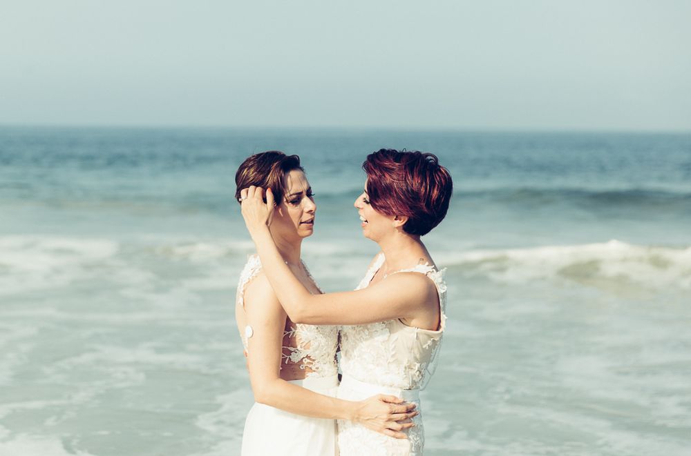 Intimate beach portrait with ocean waves and overcast sky in background.