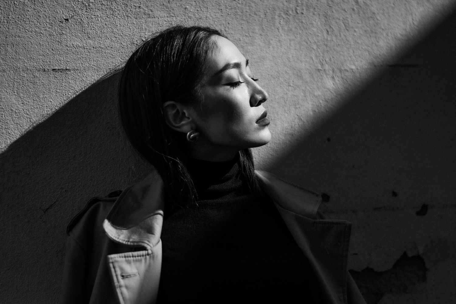 Black and white portrait with dramatic shadows and lighting creating a moody atmosphere.