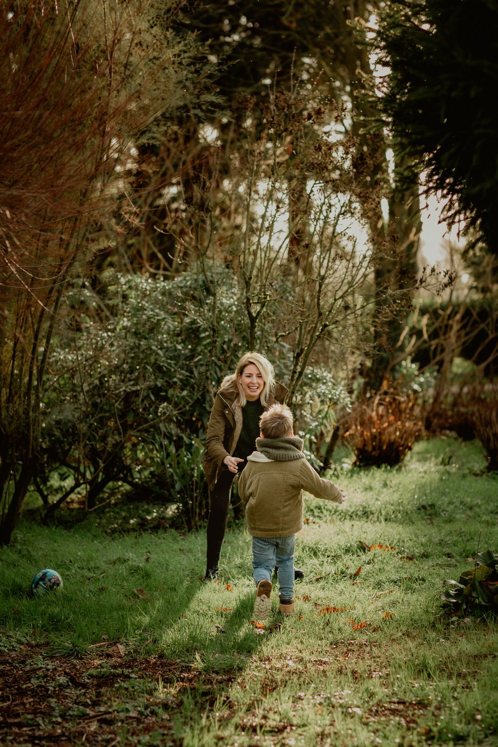Sunlight streaming through trees illuminates a playful scene in a wooded garden.