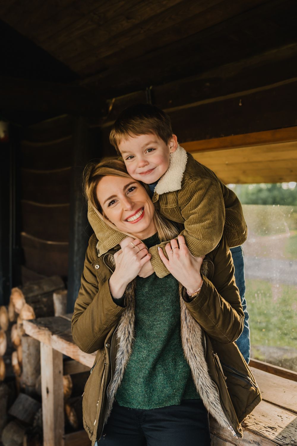 A cheerful piggyback ride moment photographed in a rustic wooden cabin setting.