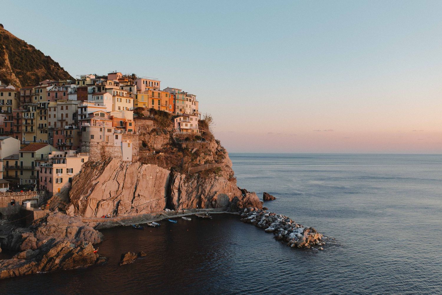 Manarola village in Cinque Terre Italy perched on cliffs above the Mediterranean Sea at sunset.