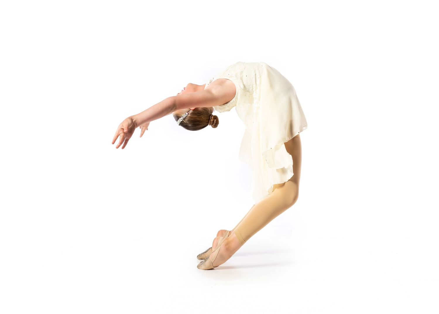 A dancer arching backward in a cream dress on a white backdrop