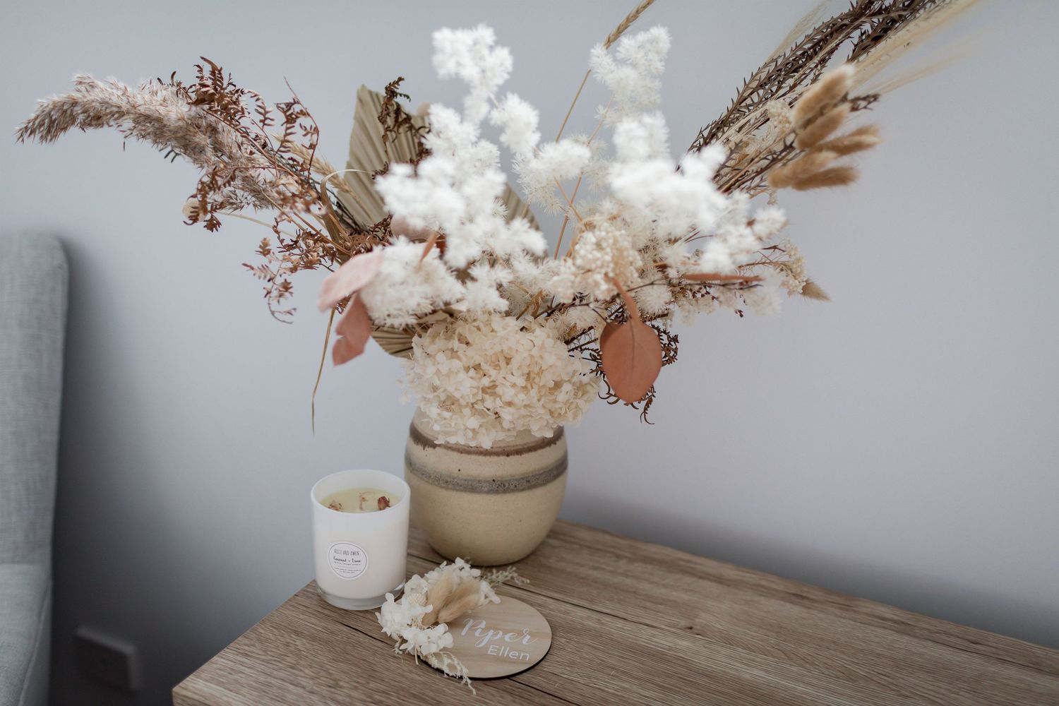 Neutral dried flower arrangement with pampas grass in beige vase on wooden table.