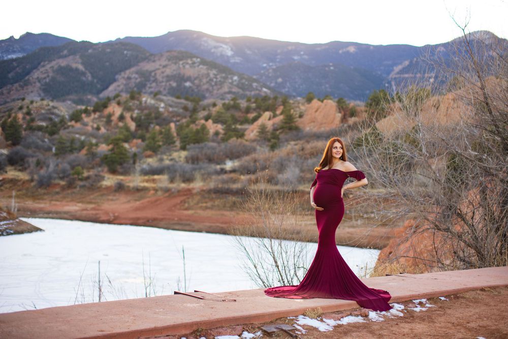Burgundy mermaid maternity gown with mountain lake backdrop.
