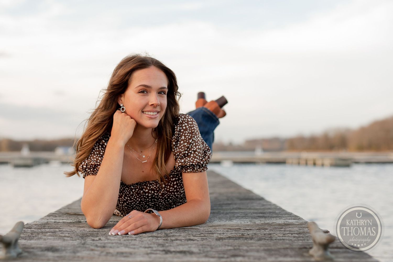 Casual portrait of someone relaxing on a wooden dock by the water during golden hour.