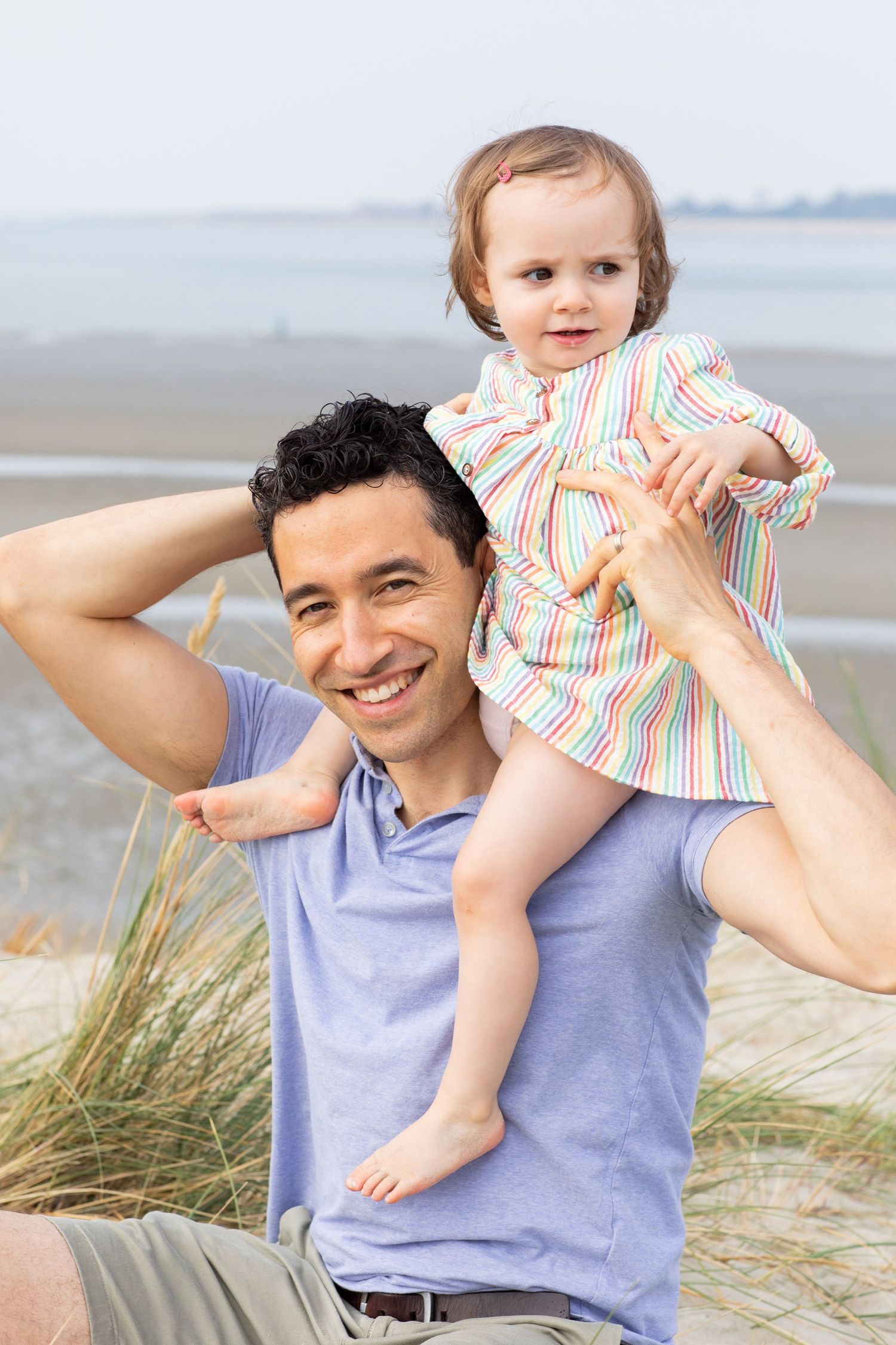 A heartwarming moment captured on a beach with dune grass and soft lighting.