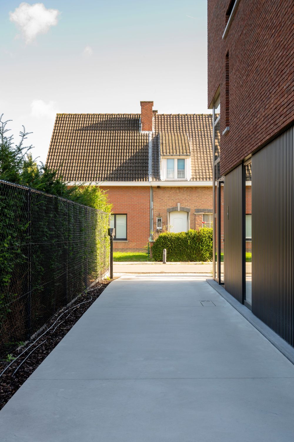Concrete driveway leading to modern brick homes with tiled roofs in a residential neighborhood.