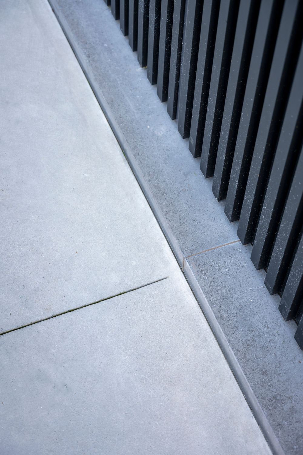 Close-up detail of sleek white concrete steps with black vertical railings.