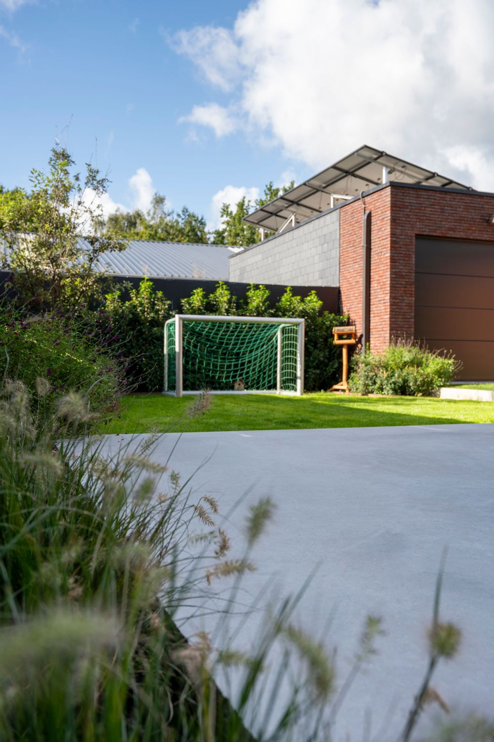 Wide concrete terrace with soccer goals and landscaping at a modern brick building complex.