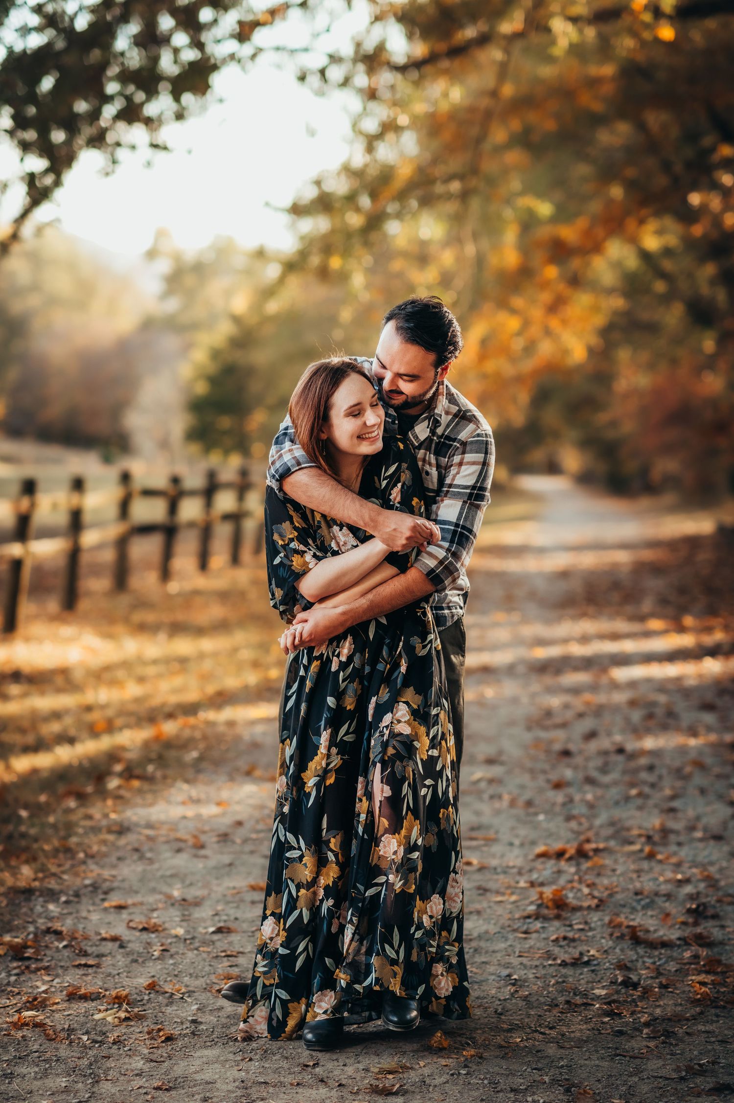 husband wraps his arms around wife on fall tree lined path for couples photos in Chattanooga