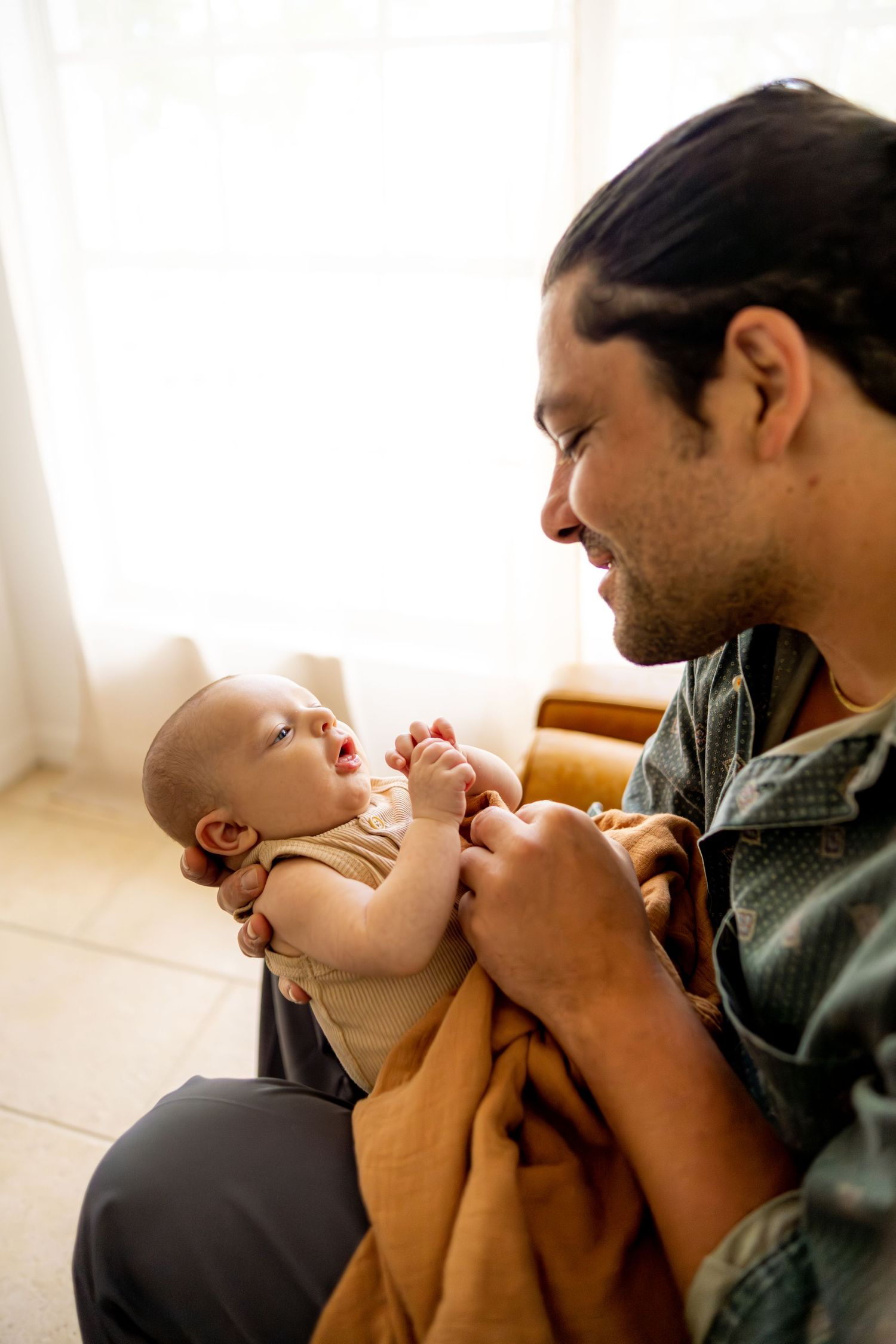 Parent in green shirt shares loving playtime moments with young baby.