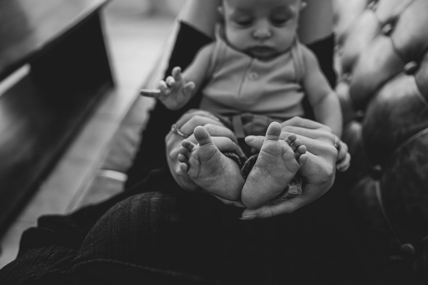 Black and white photo of tiny baby feet being held in hands.
