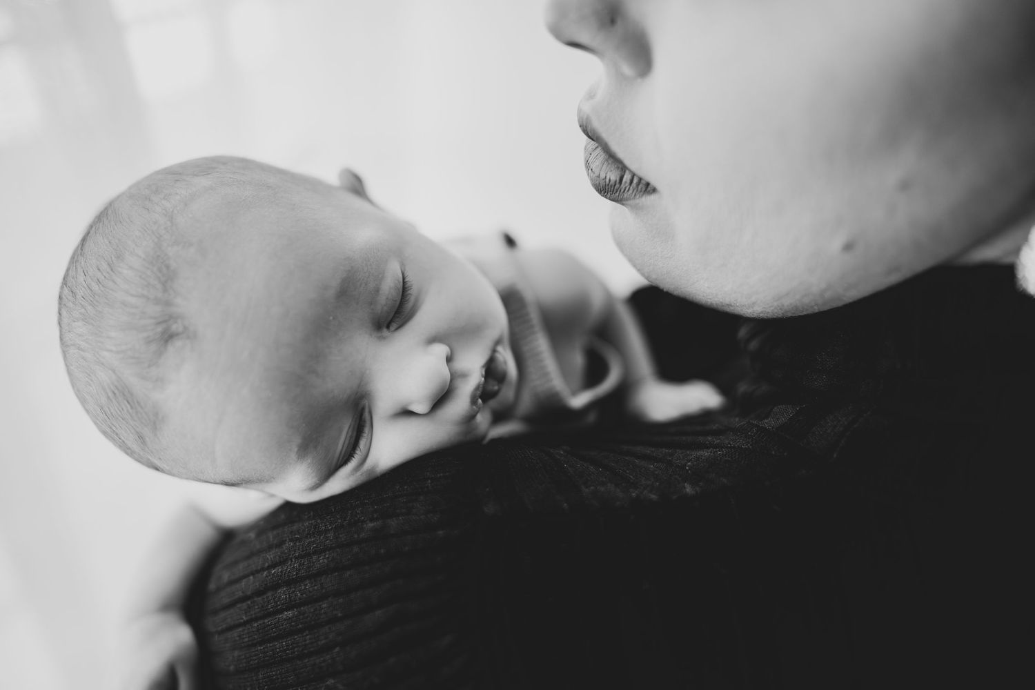 Black and white image of an infant and parent sharing an intimate bonding moment.