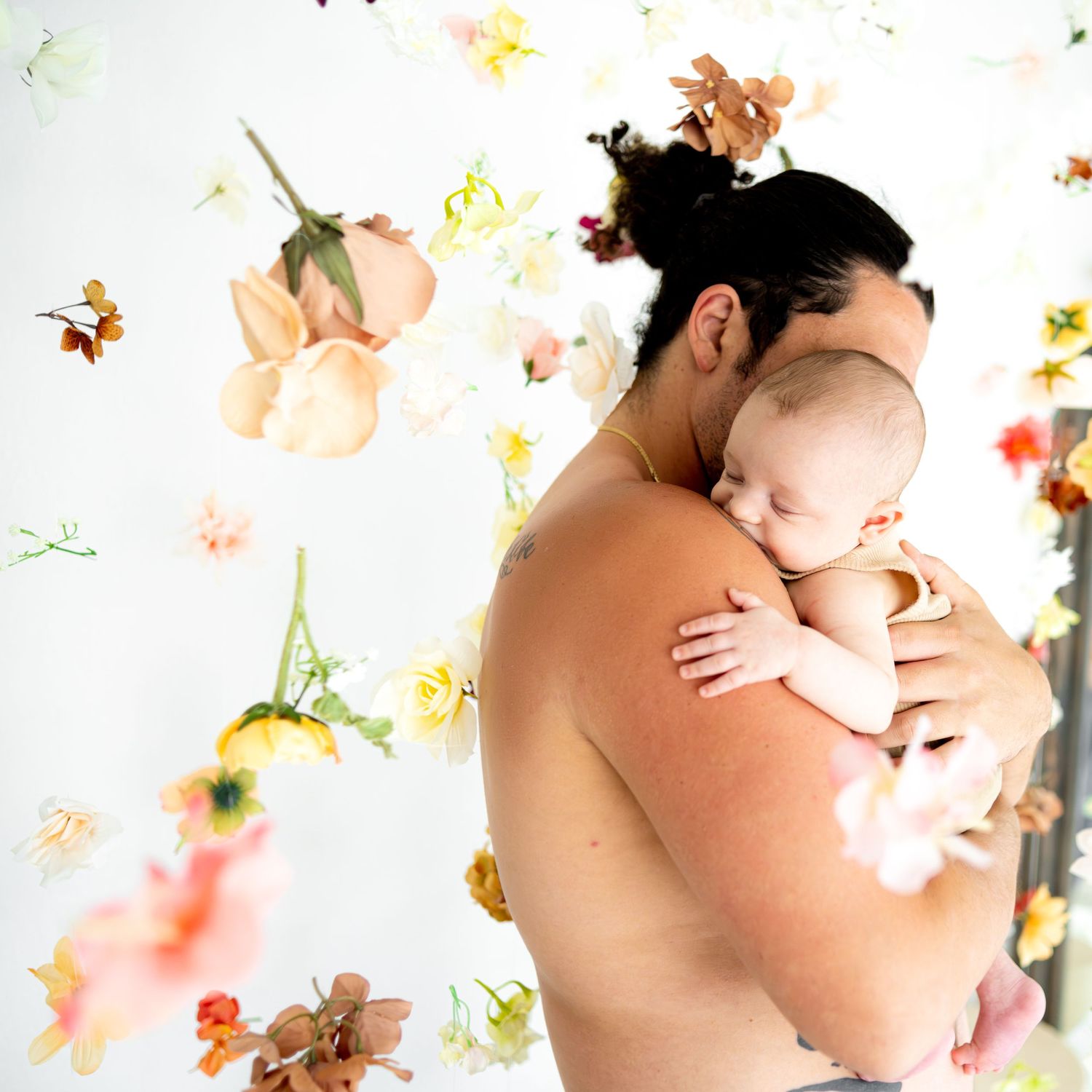 Artistic maternity photo with floral petals and leaves floating against white background.