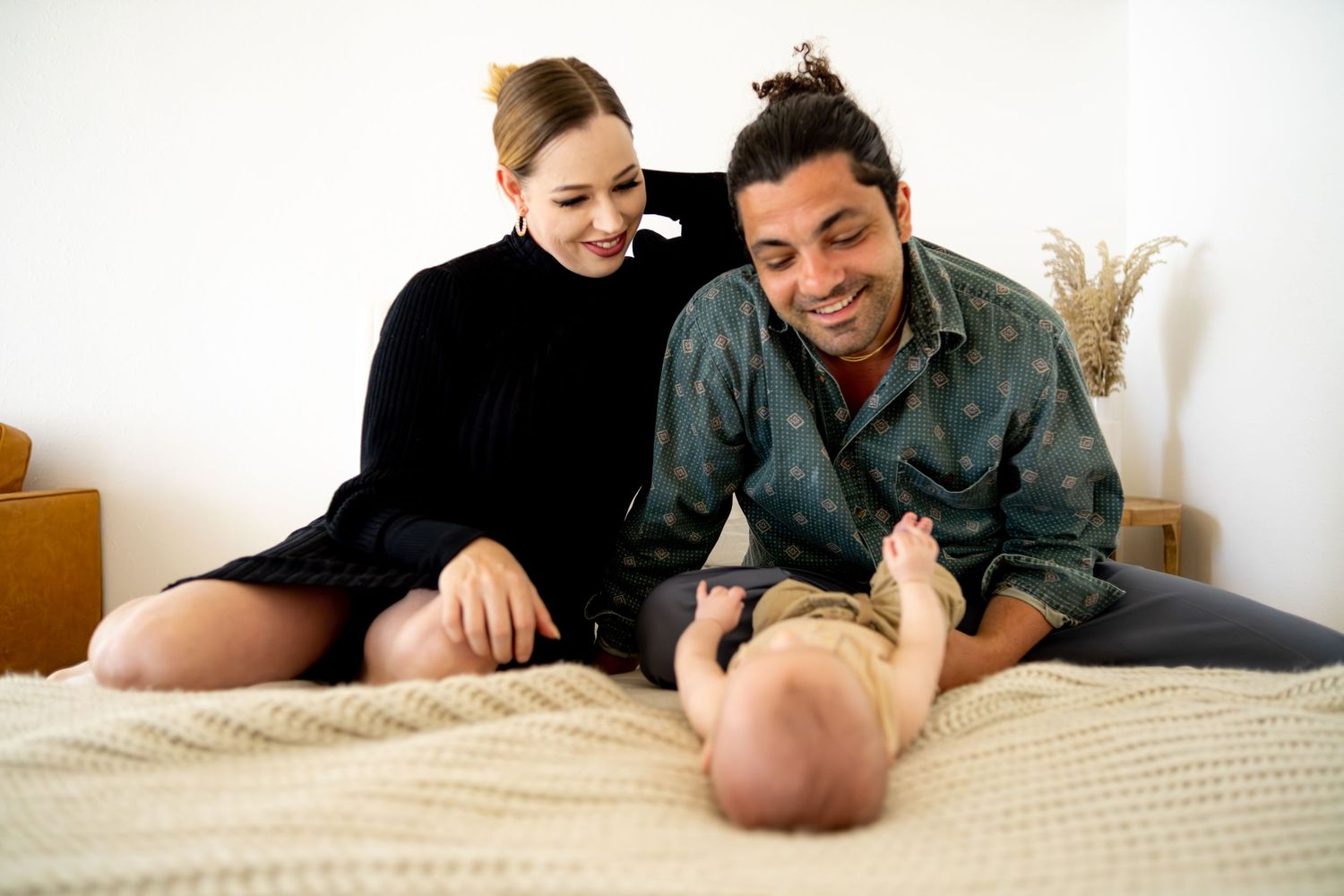 Family shares joyful moments together on white bedding.
