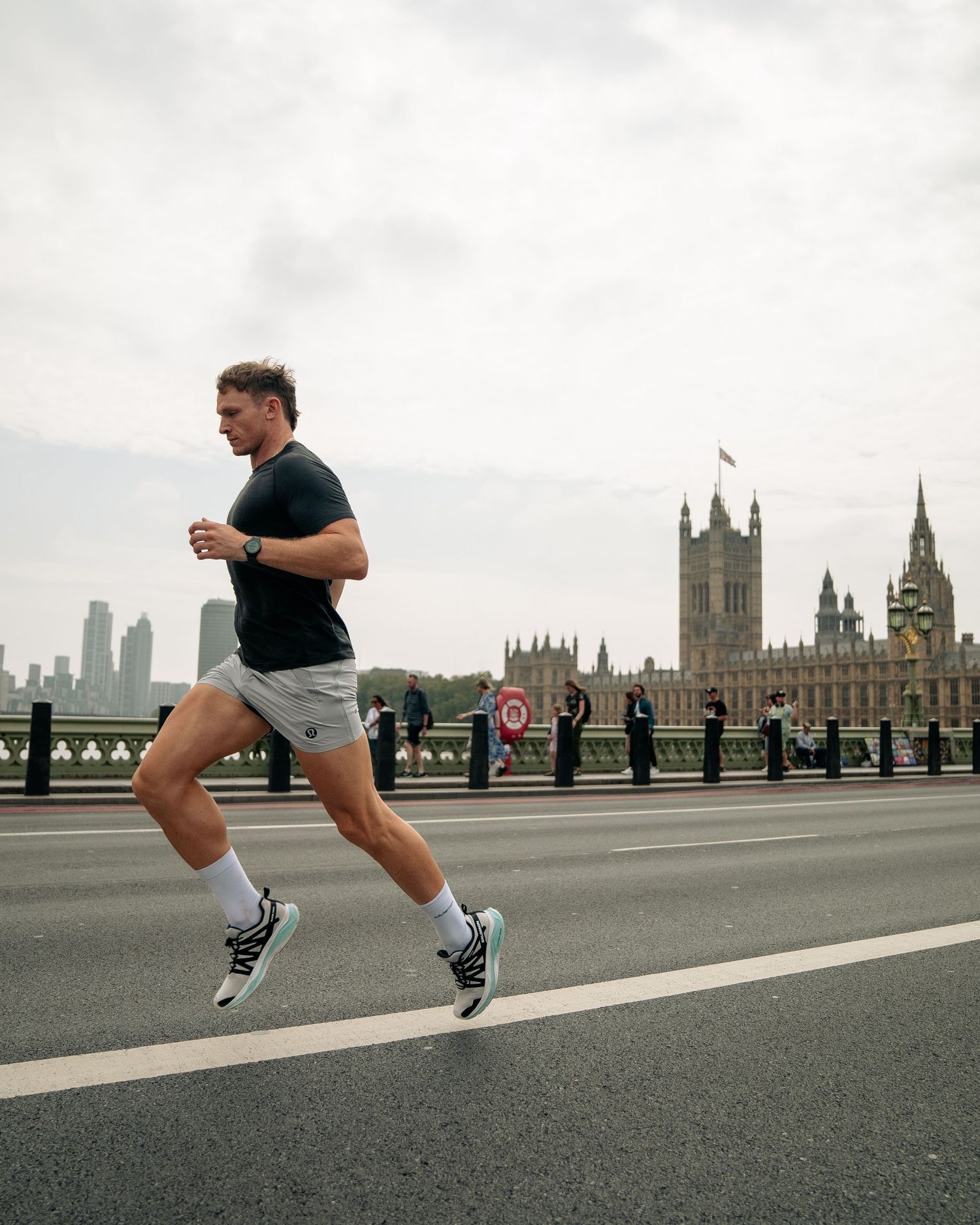 Runner jogging across bridge with Houses of Parliament visible in London backdrop.