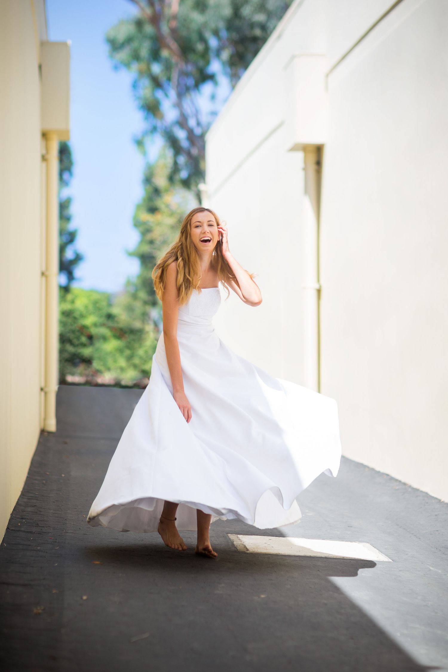 A flowing white wedding dress dances in motion along a covered walkway.