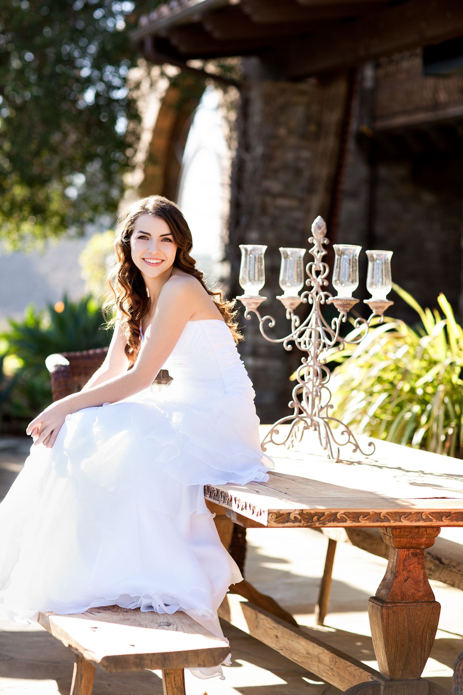 Bridal portrait with ornate candelabra on rustic wooden bench at stone villa.