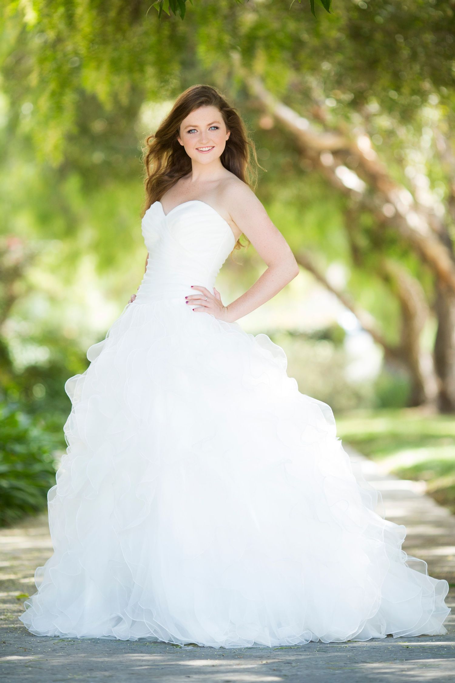 Elegant white ballgown with sweetheart neckline and flowing tulle skirt photographed in a garden setting.