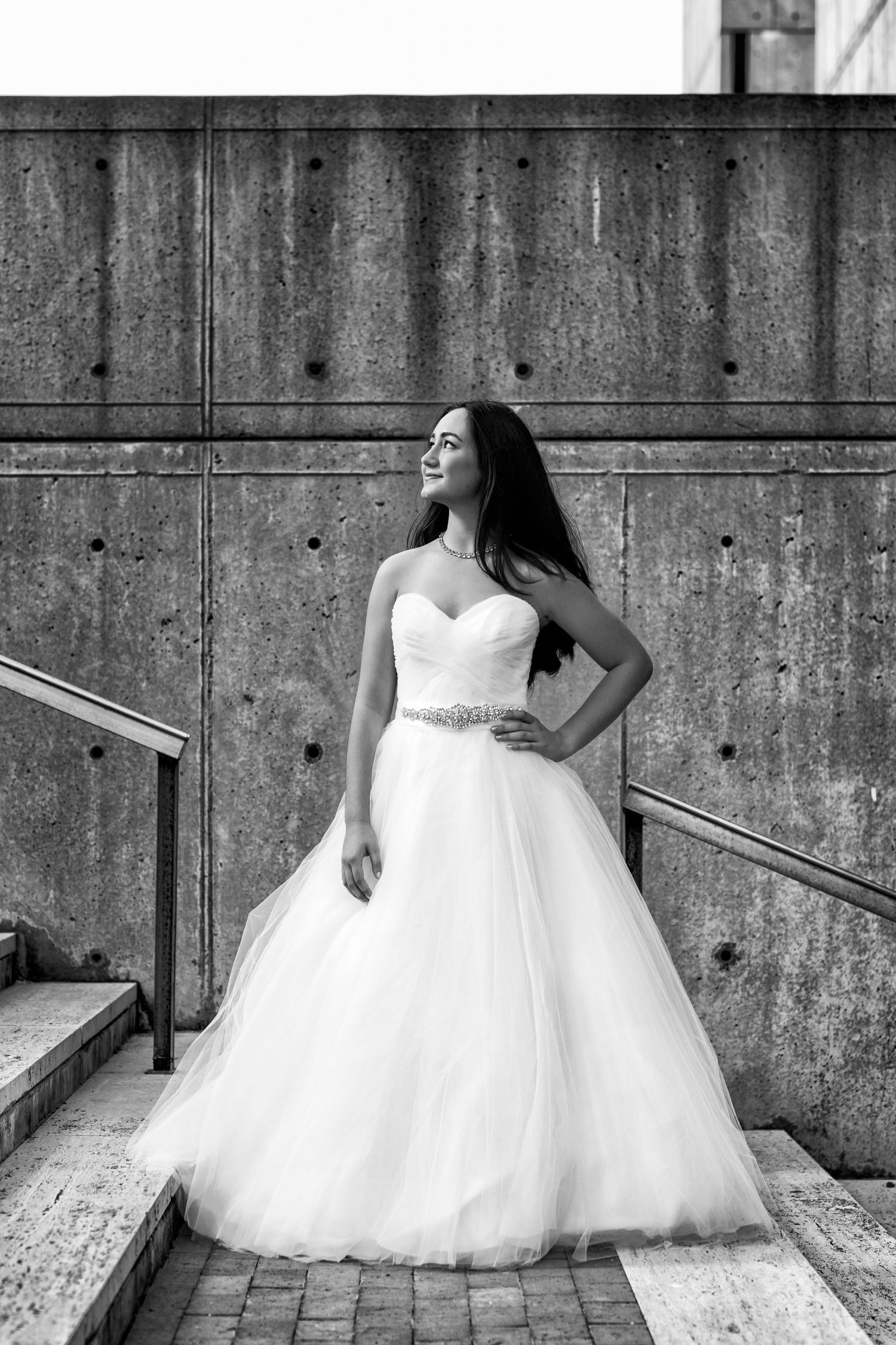 A classic ball gown wedding dress photographed against industrial concrete stairs.