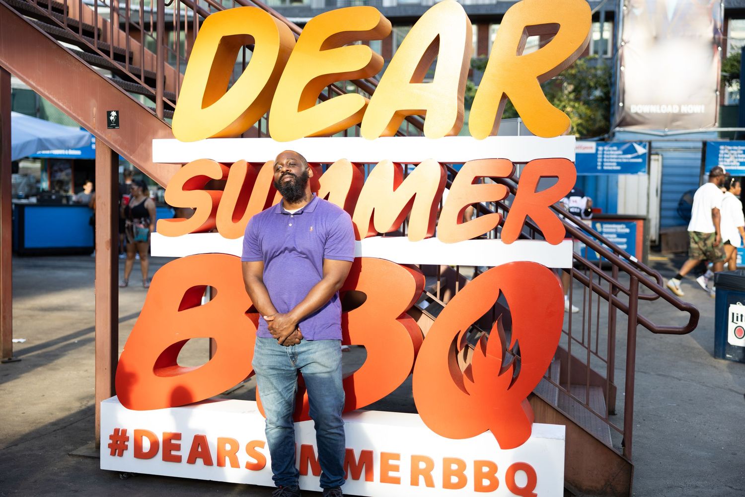 Orange and yellow 'Dear Summer BBQ' sign display at an outdoor event.