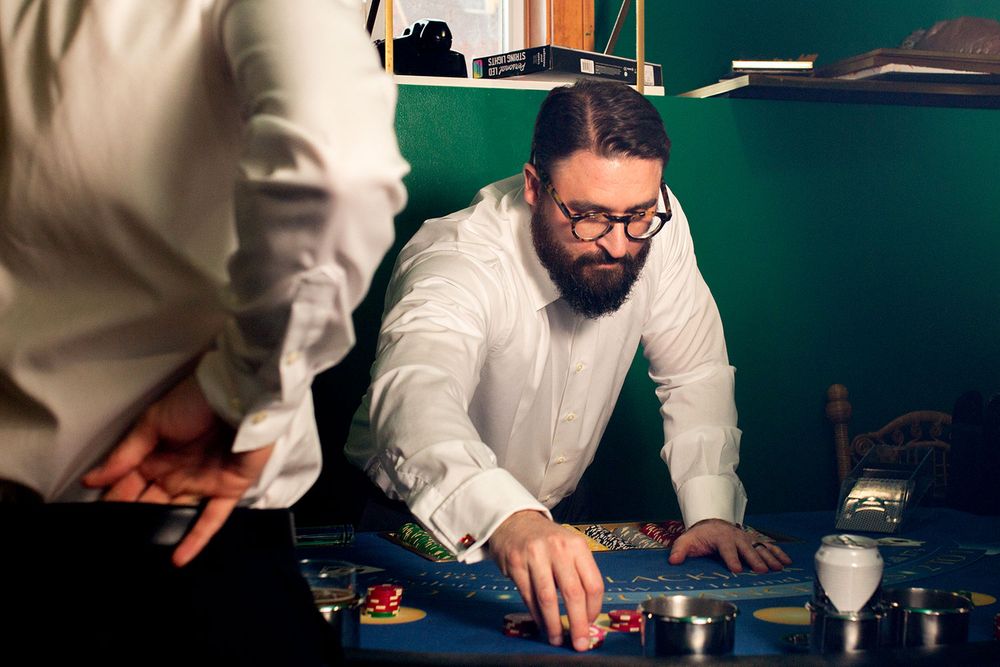 Players in white shirts lean over a blue casino gaming table during gameplay.