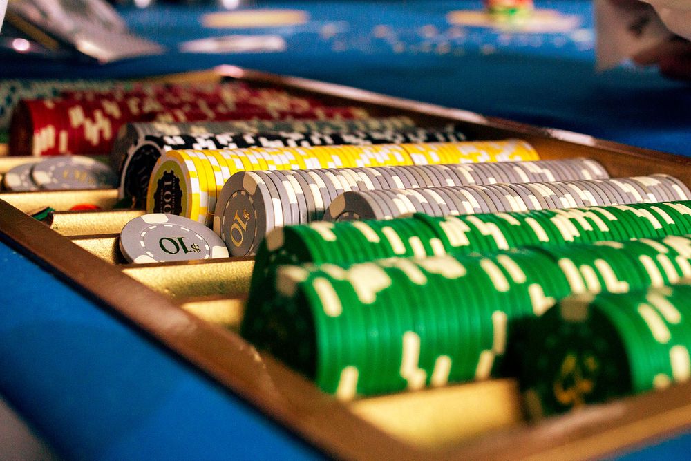 Close-up view of casino chips and playing cards on a blue felt table.
