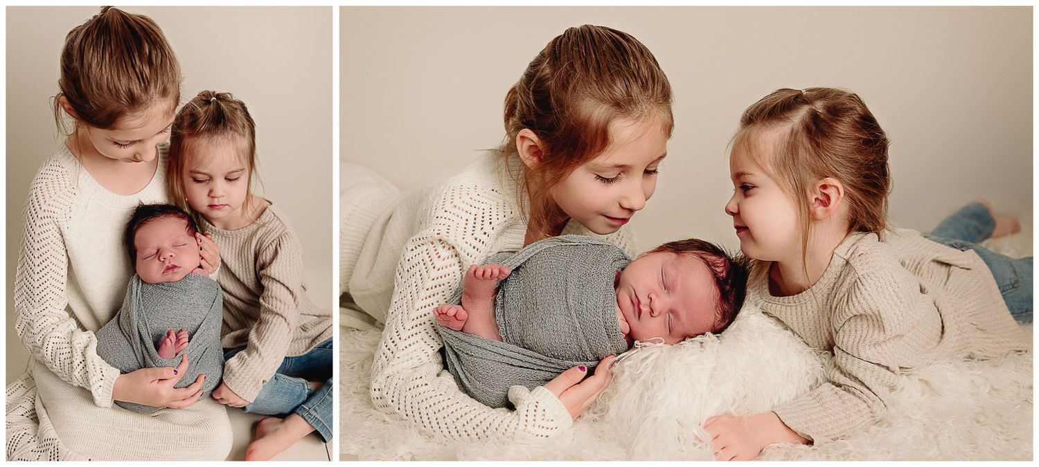 two sisters holding their baby brother during photoshoot in kansas city newborn studio