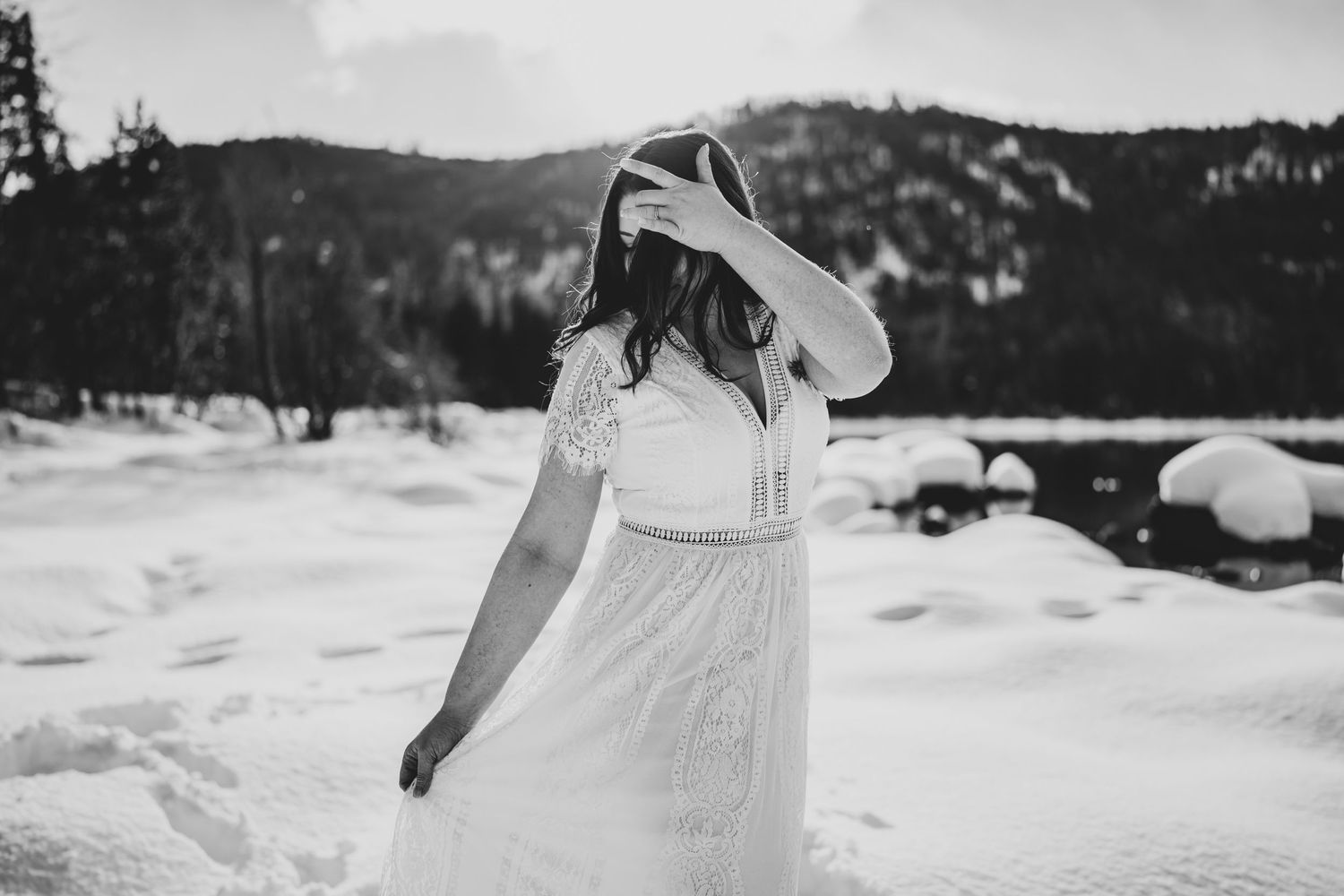 Person in white dress twirling in the snow with mountains in background.