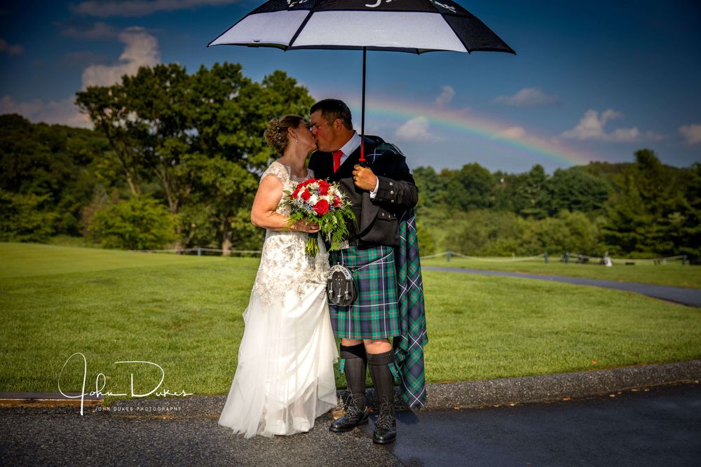 Wedding couple sharing intimate moment under umbrella in outdoor setting.