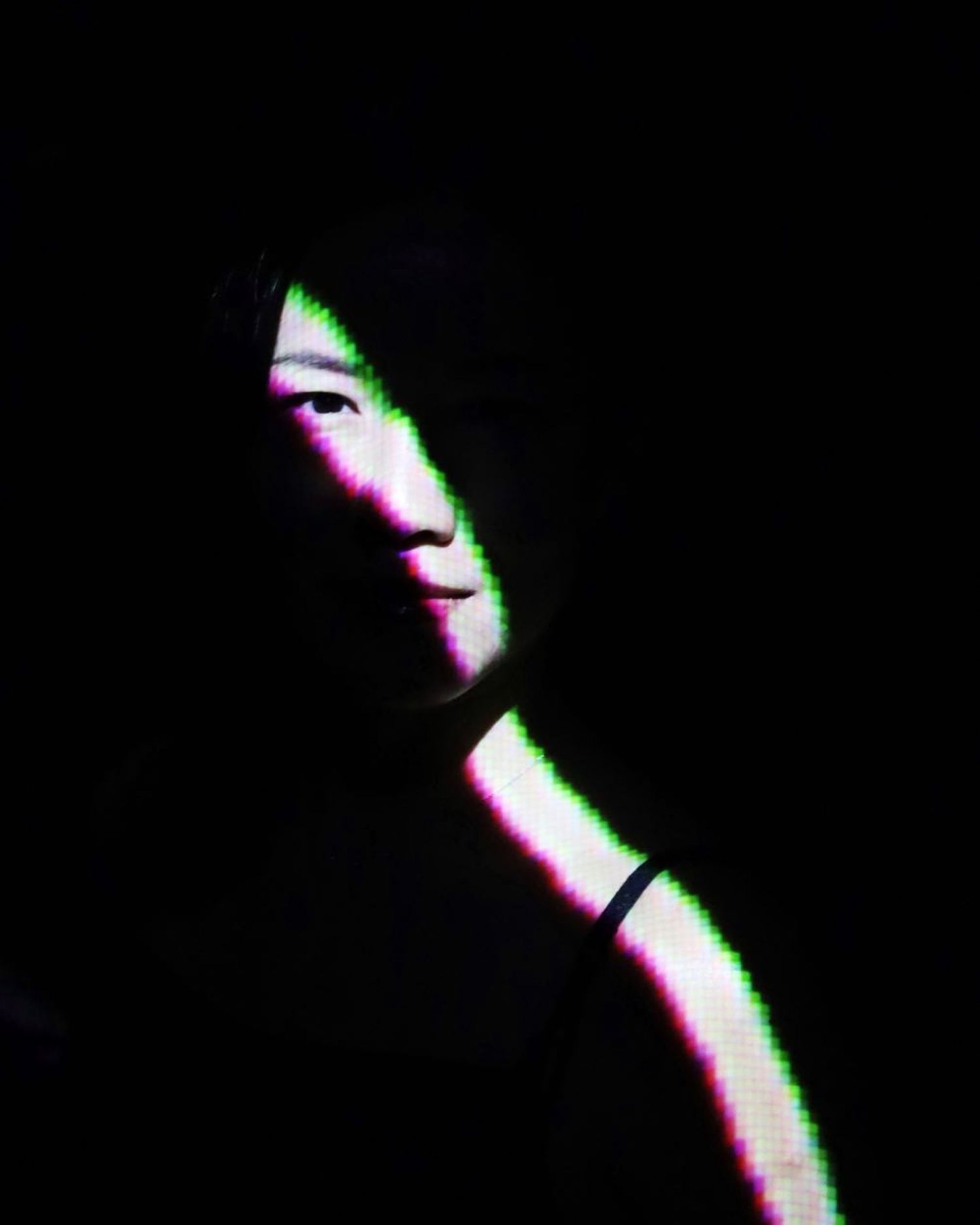 Artistic portrait with chromatic aberration effect in dark setting.