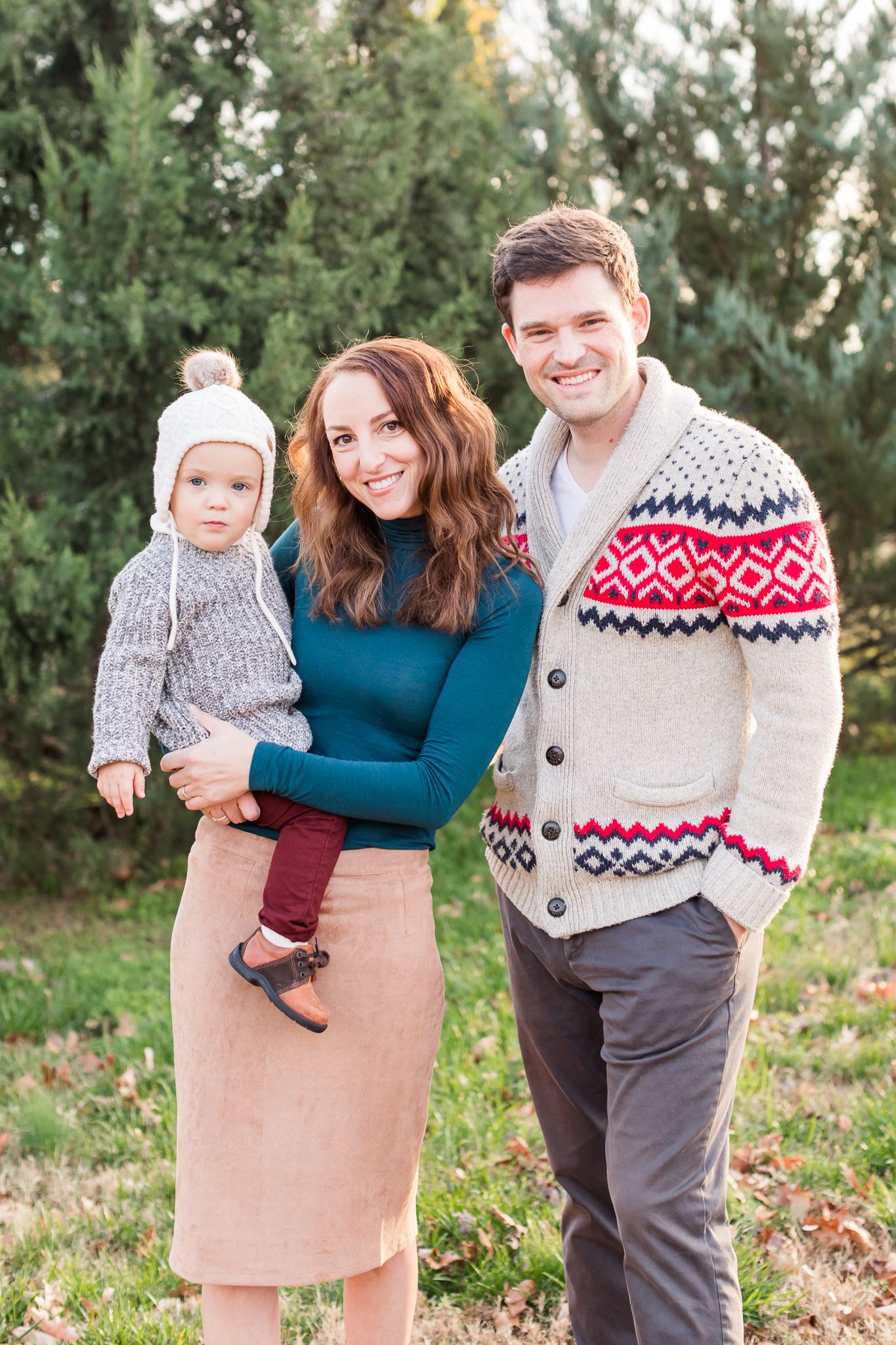 Couple with small child posing in winter with evergreens