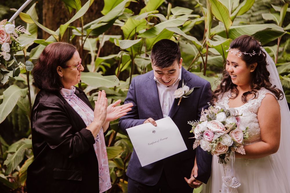 An intimate outdoor wedding ceremony amid lush greenery and tropical plants.