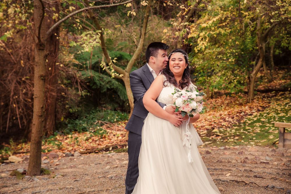 Romantic autumn wedding portrait on a leaf-covered path in the woods.