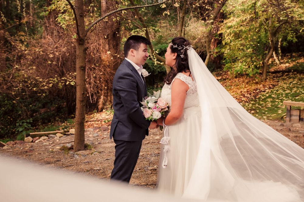 Romantic wedding moment captured in a wooded setting with a flowing veil.