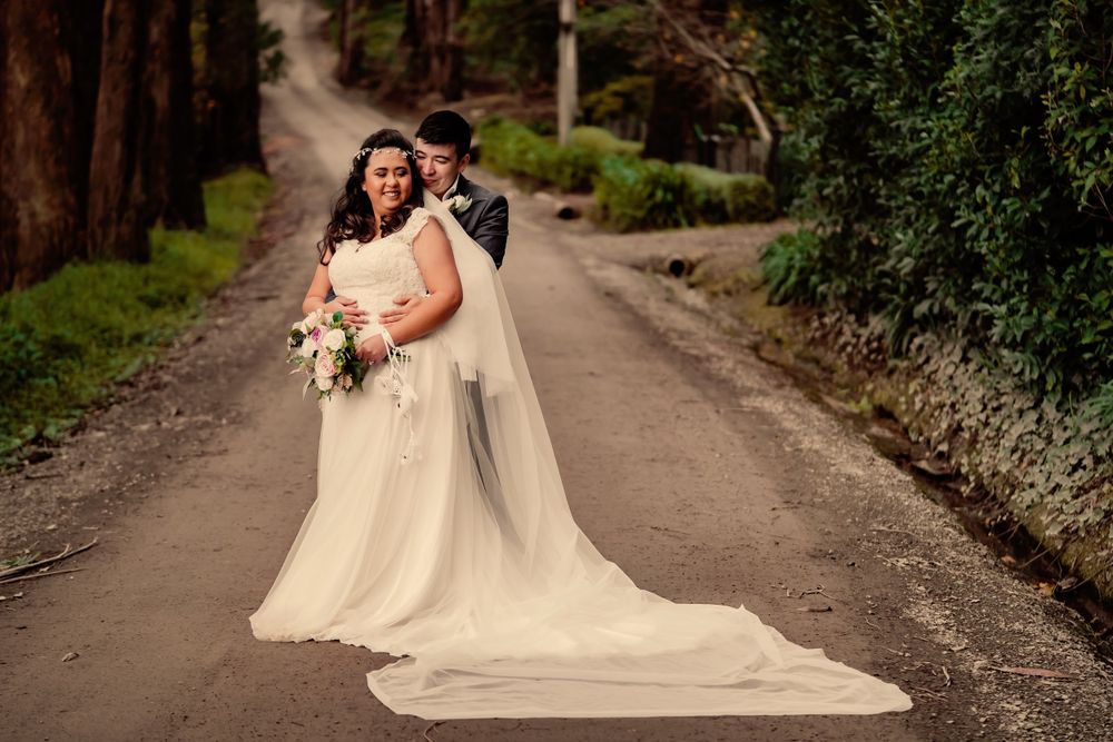 Wedding portrait on a forest path with a dramatic trailing veil.