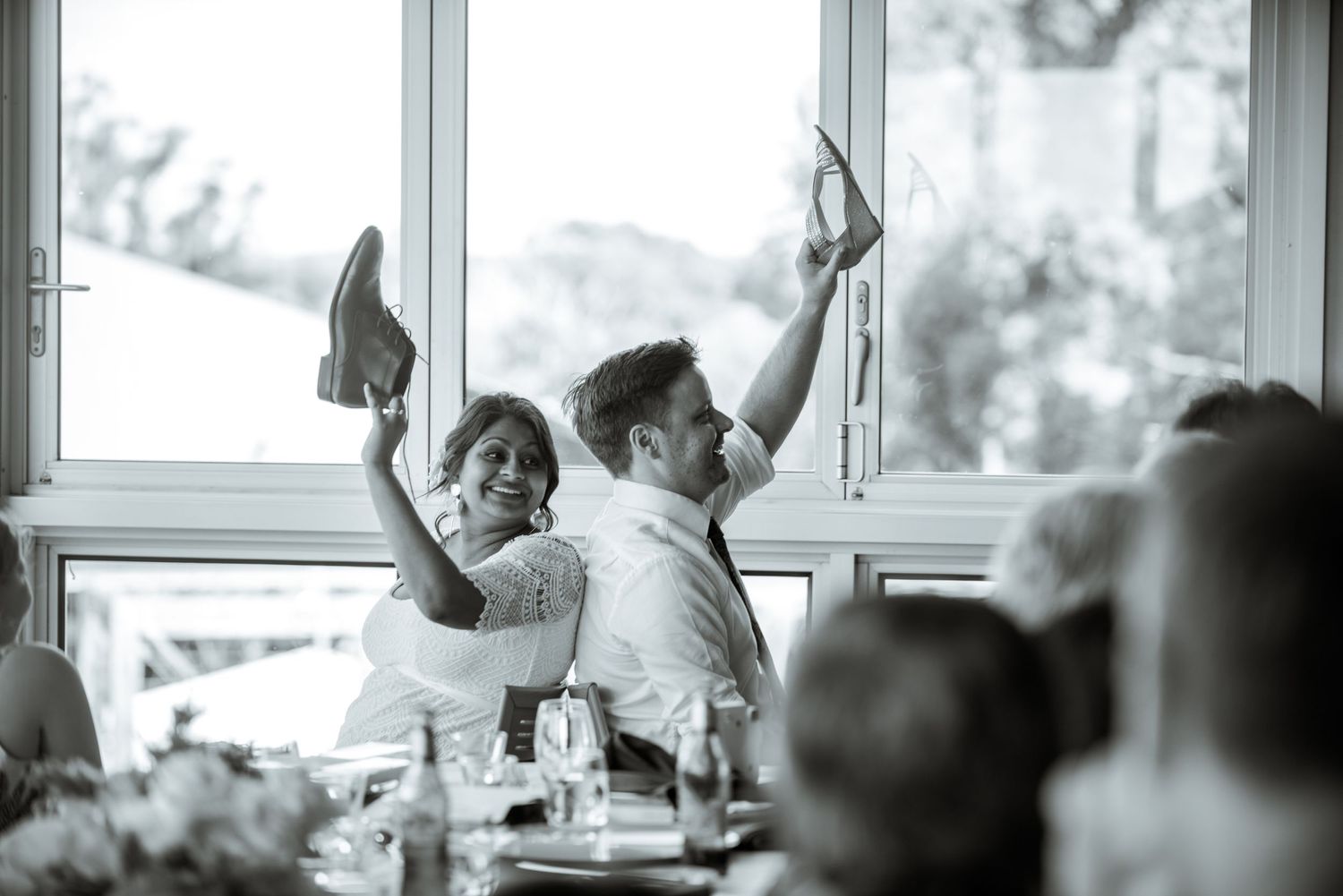 Wedding reception guests raising their shoes in a celebratory toast moment.