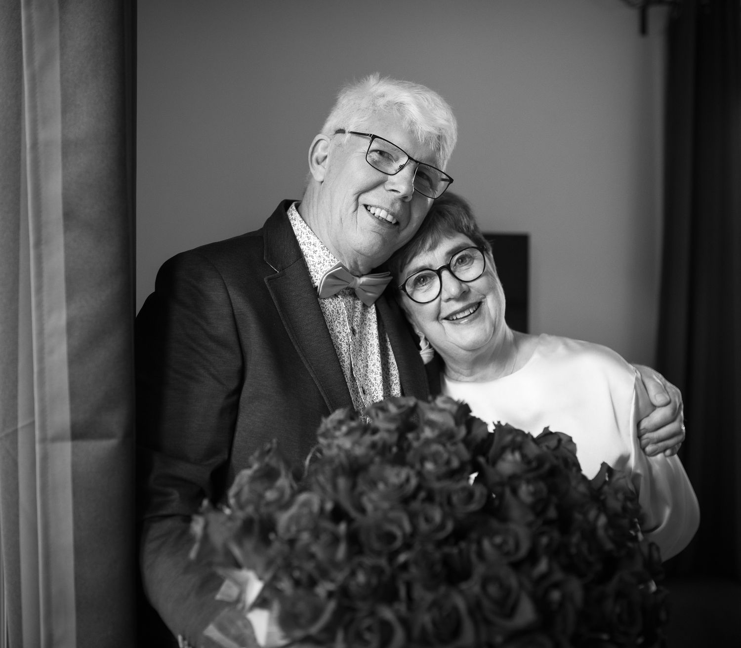Black and white portrait of happy couple with roses in intimate moment.