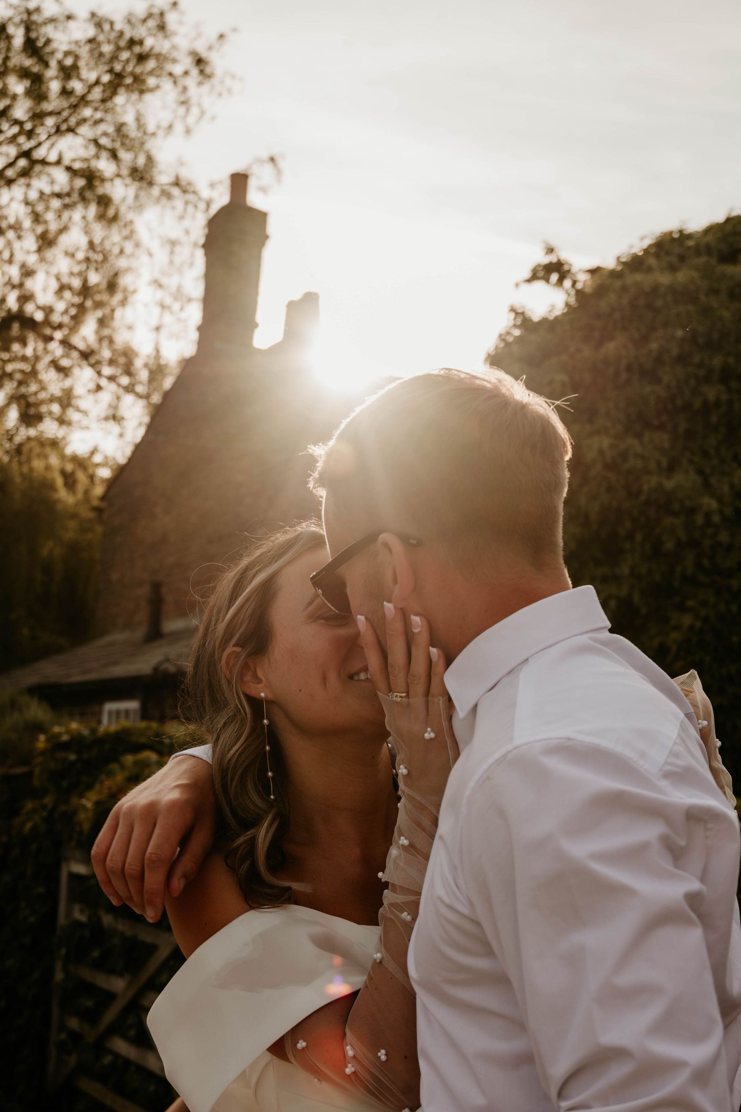 Sunset silhouette captures intimate wedding couple moment in golden light.