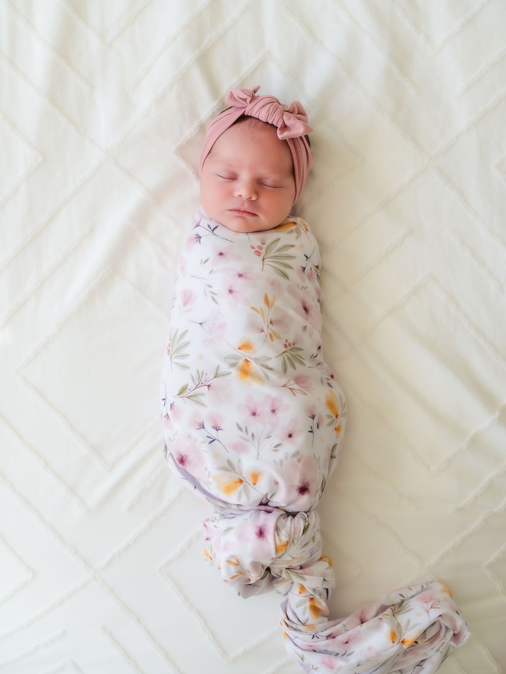 newborn baby swaddled with a bow and laying on a bed. newborn session. Sonoma county