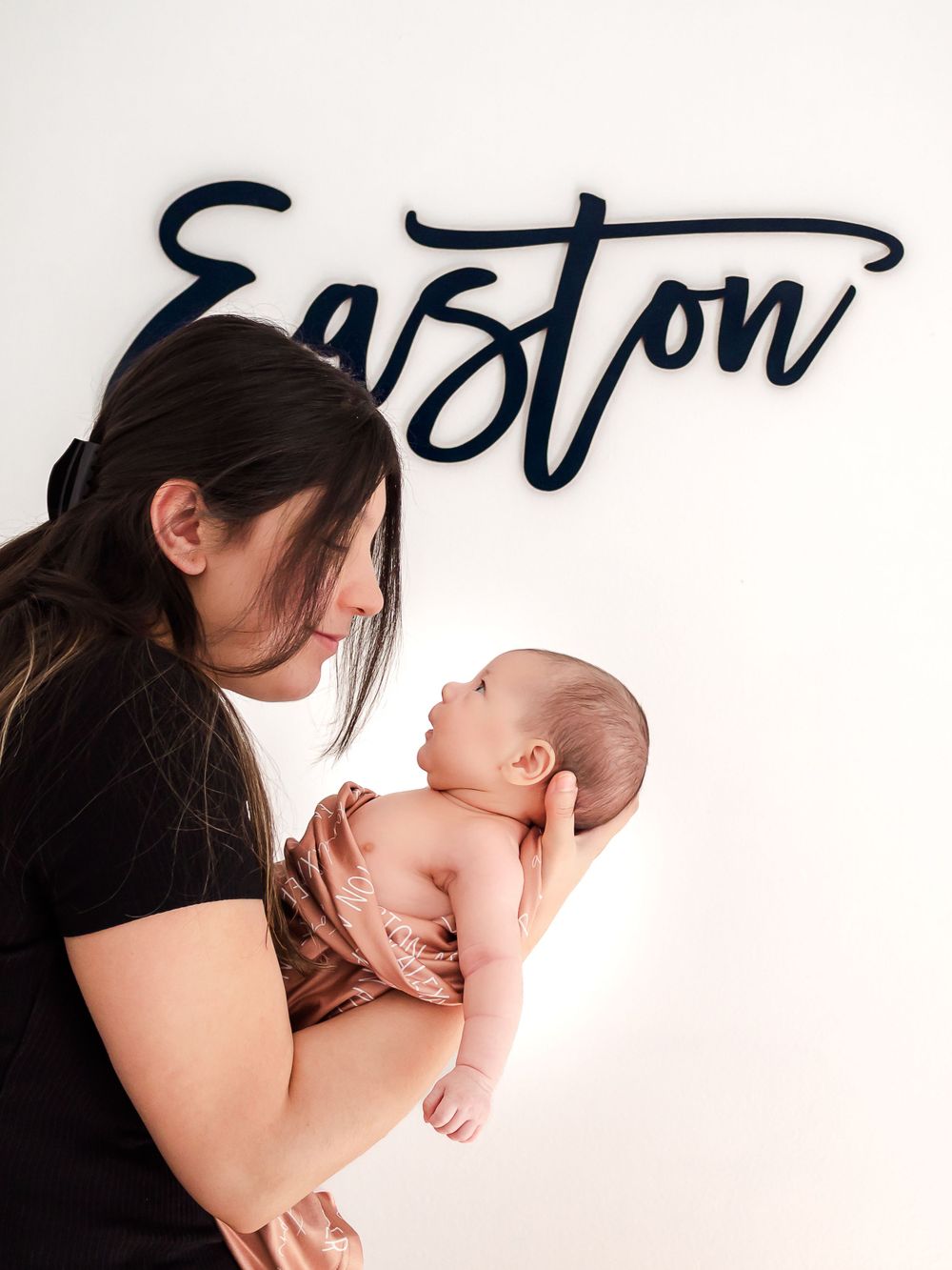 mom holding baby against a wall in nursery. newborn photos Sonoma County
