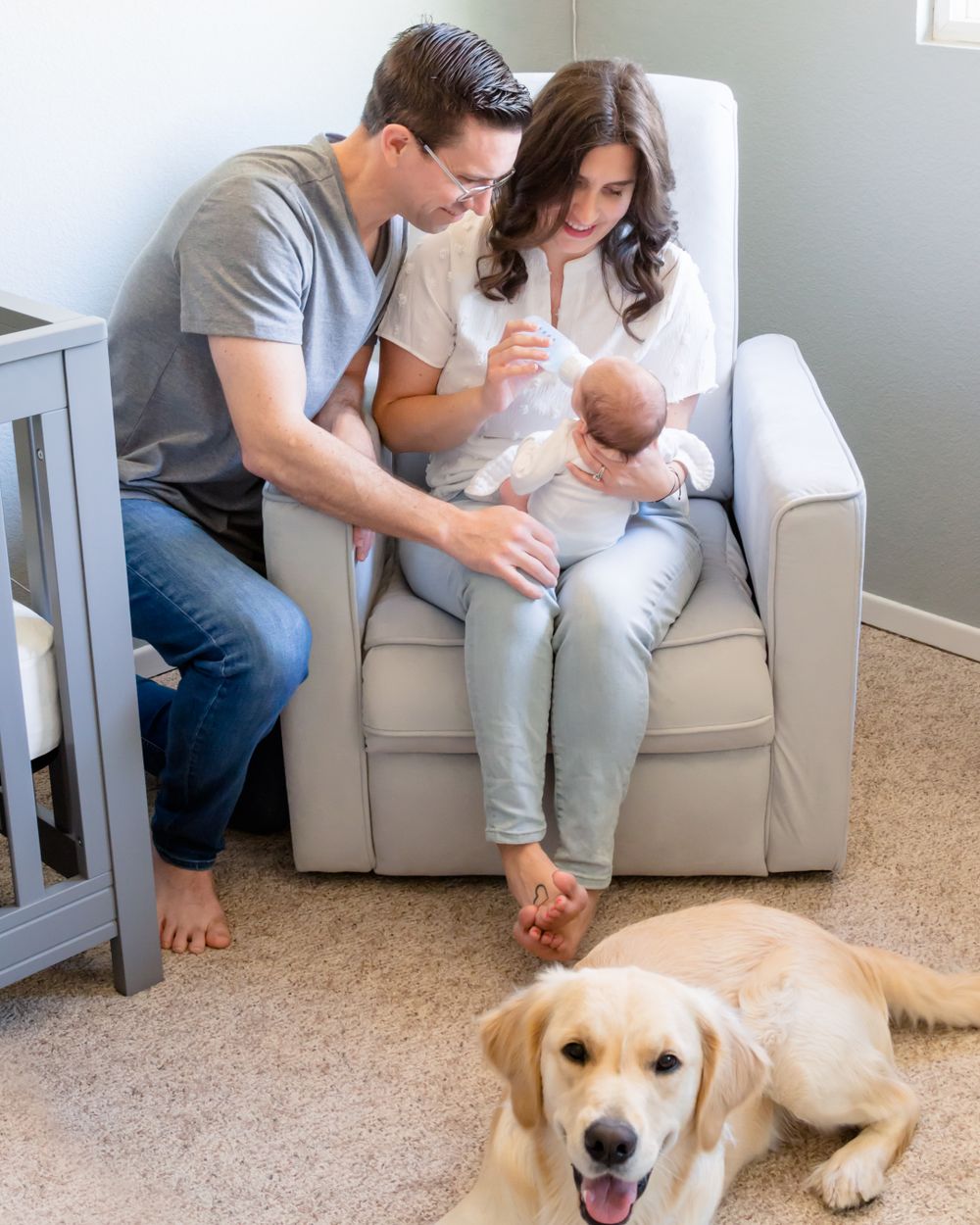 newborn baby in nursery. family sitting in rocking chair with dog nearby. in-home newborn session