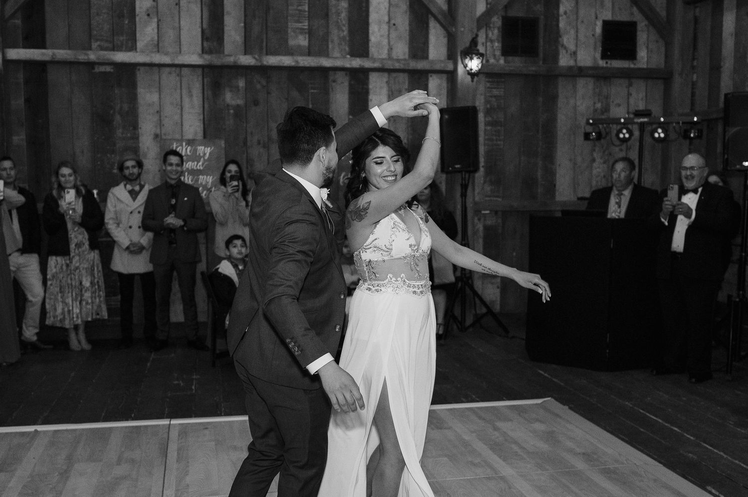 A black and white photo shows dancers performing a twirl on a wooden dance floor.