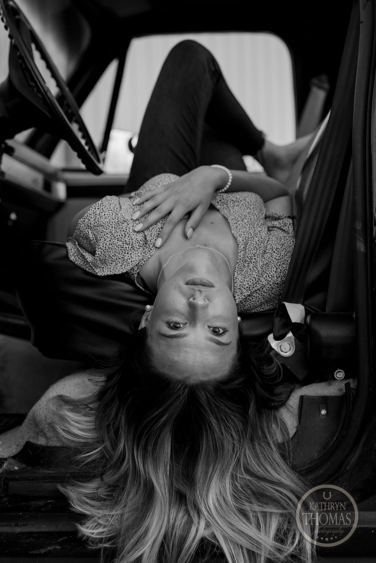 Black and white artistic portrait with dramatic lighting inside a vintage vehicle.