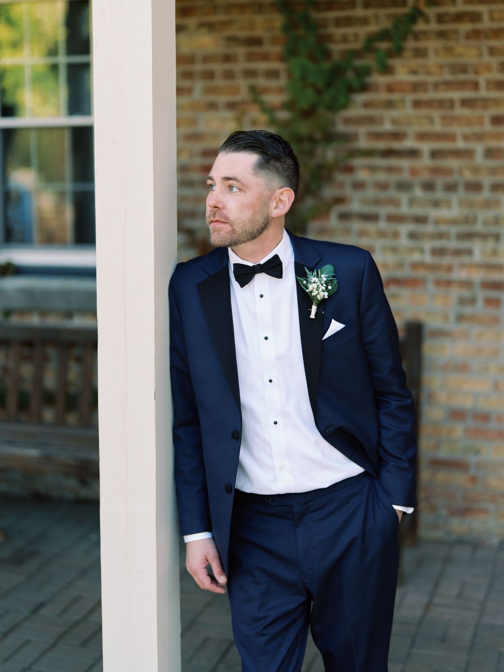 Candid portrait of a groom outdoors with bow tie and a blue suit.  Classic and film-inspired wedding photography in Madison, Wisconsin.