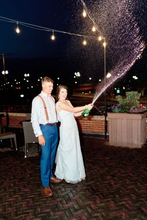 Bride and groom popping champagne at night at Hotel Julien. Classic and film-inspired wedding photography in Madison, Wisconsin.