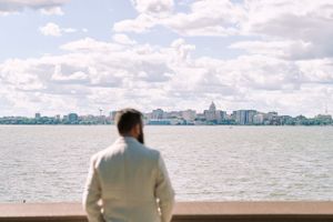 Portrait of a groom overlooking Lake Monona with Madison skyline. Classic and film-inspired wedding photography in Madison, Wisconsin.