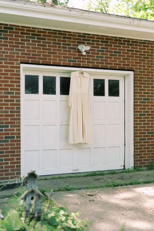 Retro wedding dress detail hanging in front of a brick home. Classic and film-inspired wedding photography in Madison, Wisconsin.